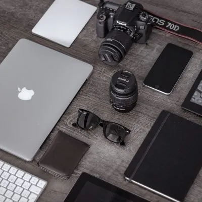 Laptop, camera, phone and notebook on a desk