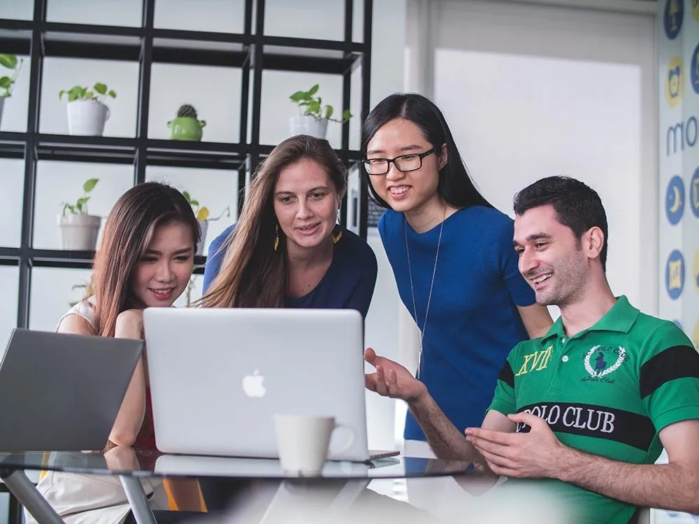 Four young people looking at a laptop together