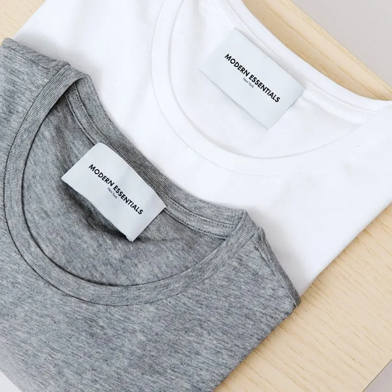 Folded white and grey T-shirts with clothing labels