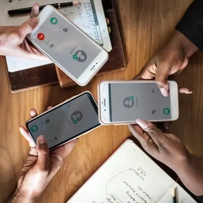 Hands holding smartphones on a wooden table